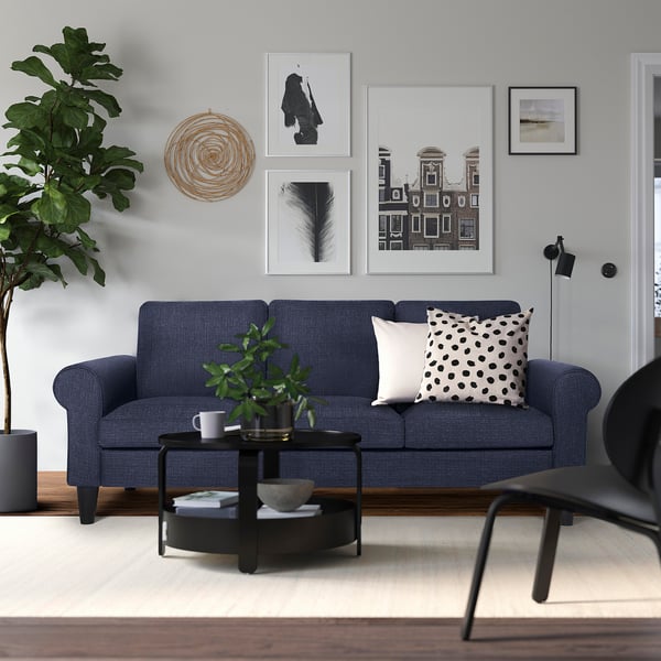 Modern living room with blue GAMMALBYN sofa, black coffee table, wall art, and plants. Sofa fits well in medium-sized room.