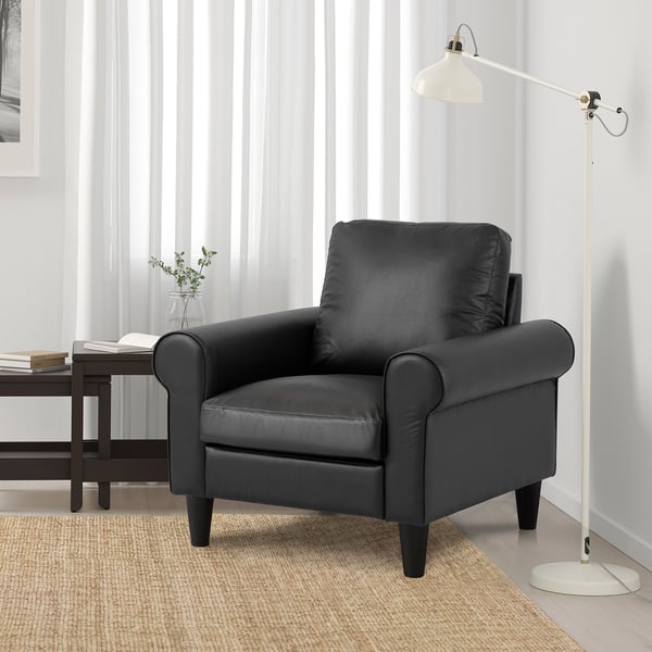 GAMMALBYN black leather armchair, tall and comfortable, beside a floor lamp and small plant in room.