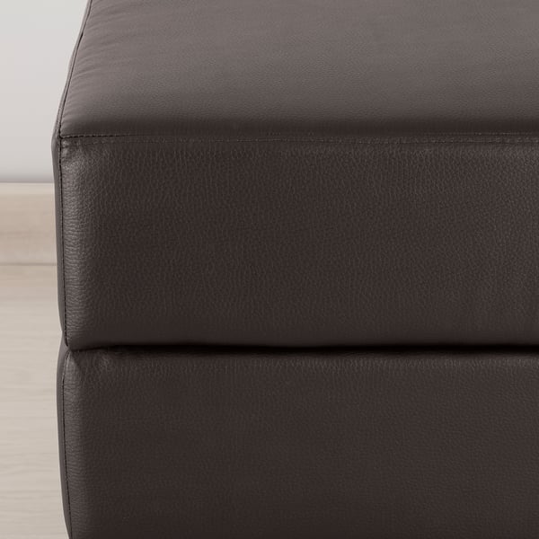 Close-up of smooth, dark, gammalyn footstool. Shows thick cushion top, stitched in durable material.