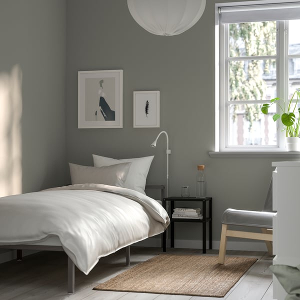 Minimalist bedroom a white GRIMSBU bed frame under a window, with grey walls and decor. The compact bed fits well in small spaces.
