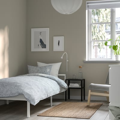 Minimalist bedroom with GRIMSBU bed, side table, lamp, plant, art, white lampshade.