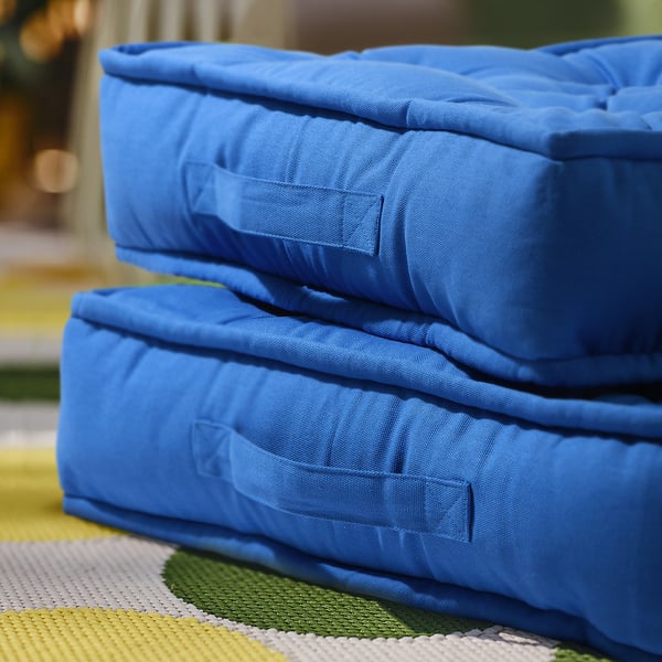 Two blue GURLI floor cushions, stacked, square shape, on colourful rug, soft, cotton cover.