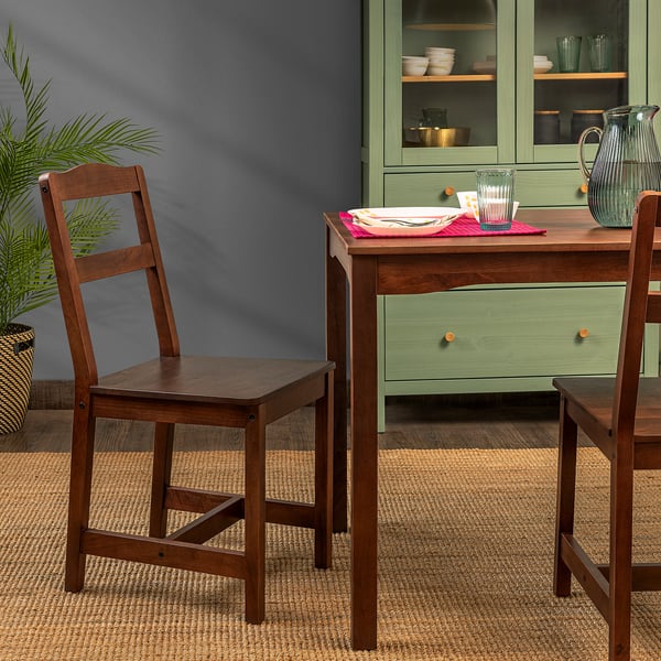 Two wooden chairs and a green table with a plate and glass, suitable for small spaces and durable for indoor use.
