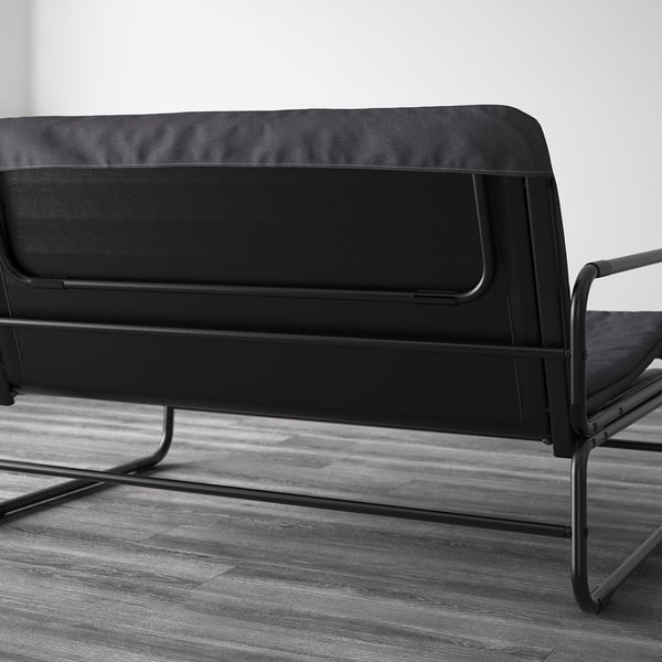 Black sofa bed with metal frame, capable of transforming into a bed for two, shown in a modern room setting.