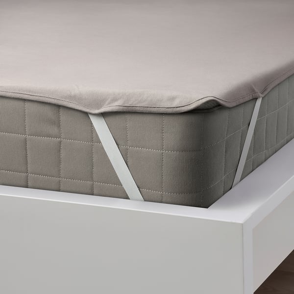 Grey waterproof mattress protector with elastic corners on a white bed.