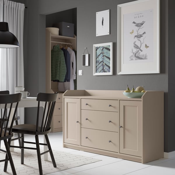 Modern living room with beige HAUGA sideboard, black chairs, grey walls, wall art, and open closet.