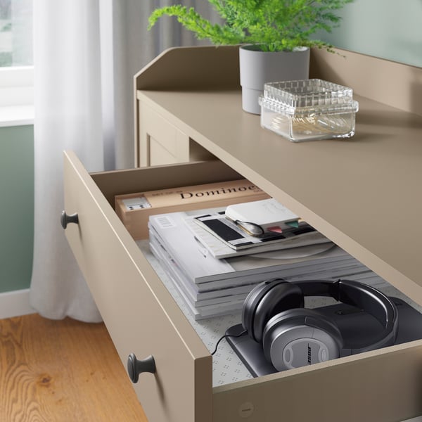 Light-colored wooden dresser drawer open showing headphones and books; modern design.