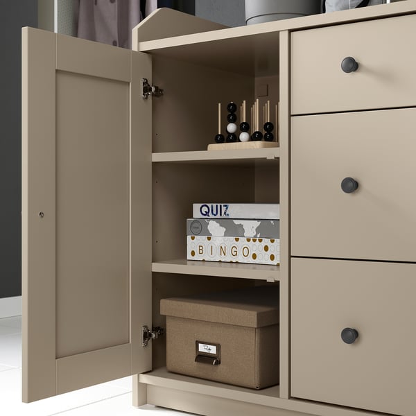 HAUGA beige cabinet with board games and box inside, light wood finish.