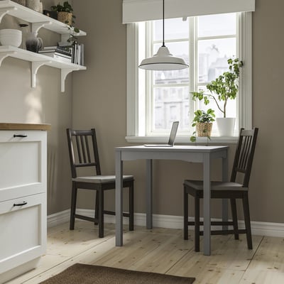 Small modern kitchen setup with a HAUGA grey table and dark chairs, complemented by a white cabinet and window, ideal for compact spaces.