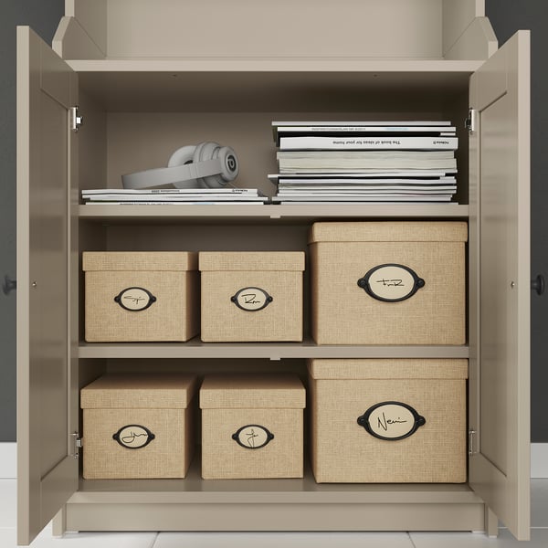 Open beige storage cabinet with books and woven storage boxes.