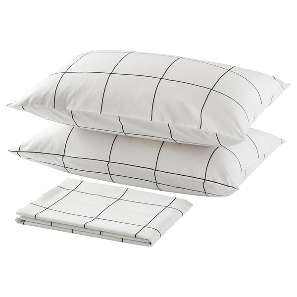 Three white pillows with black grid lines, two stacked and one folded, minimalist bedroom decor.
