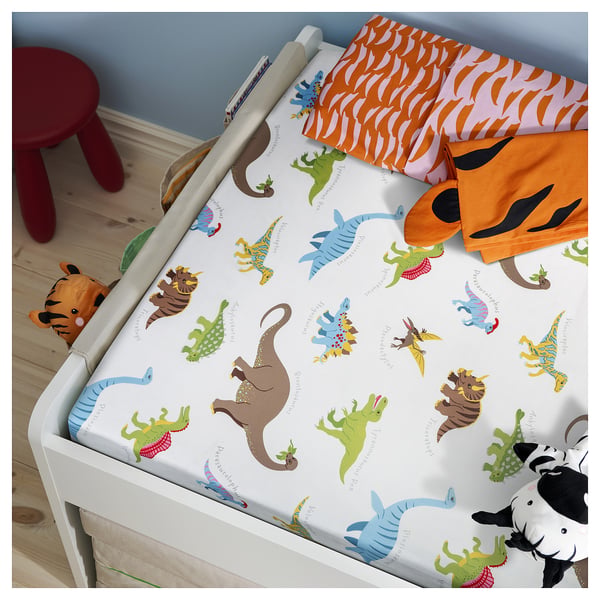 Childrens white bed with dinosaur-themed bedding, including orange and purple linen, and toys.