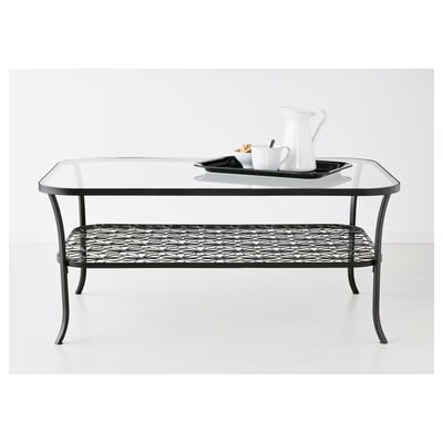Glass-top coffee table with wire shelf, holding tray, pitcher, and cups.