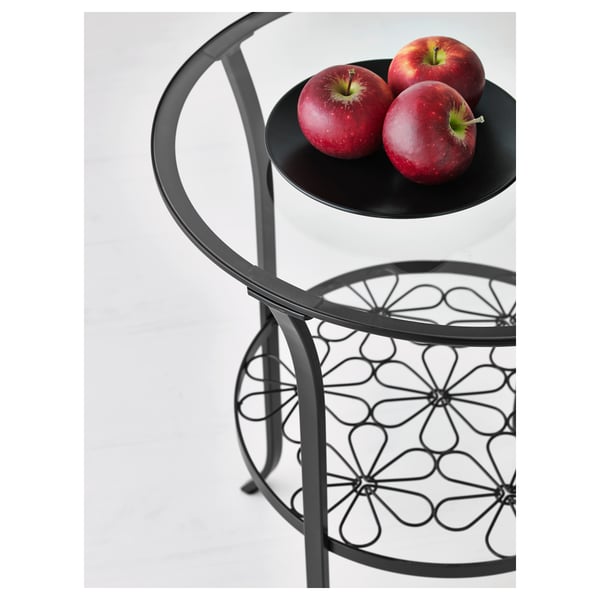 Modern metal and glass side table holds three red apples on top, showcasing elegant design.