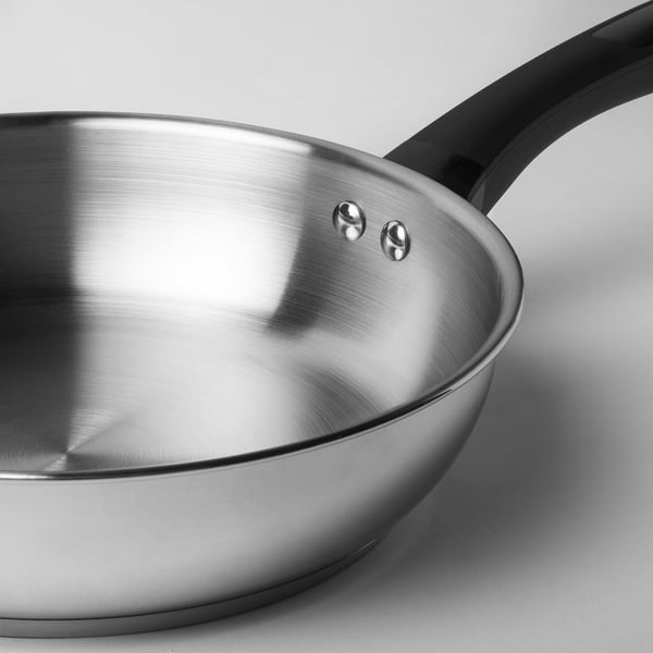 Stainless steel frying pan with black handle; sleek, durable, and reflective finish. Two riveted spots secure the handle.