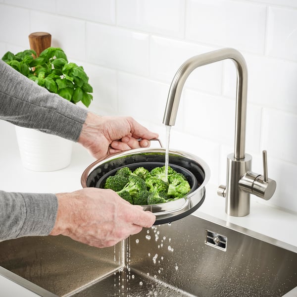 Person washes broccoli in sink using KLOCKREN silicone colander.