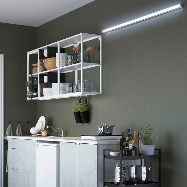 Modern kitchen with led batten light providing strong, cool light; shelves with dishes and plants.
