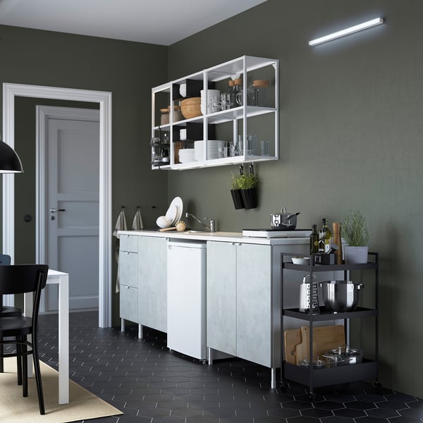 Modern kitchen with led light, grey cabinets, black floor tiles, hanging plants, and a metal cart with items.