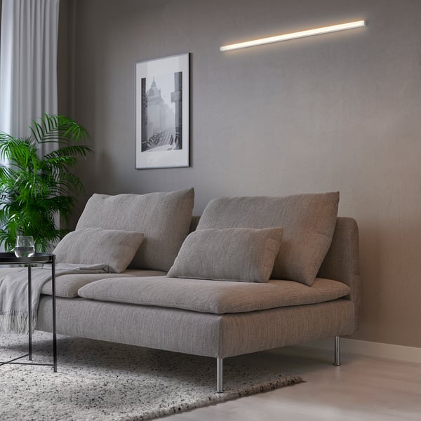Modern living room with grey sofa, pillows, plant, and wall-mounted led light fixture.