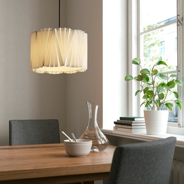 Modern dining setup with wooden table, grey chairs, KNOPPSLINGA light, plant by window.