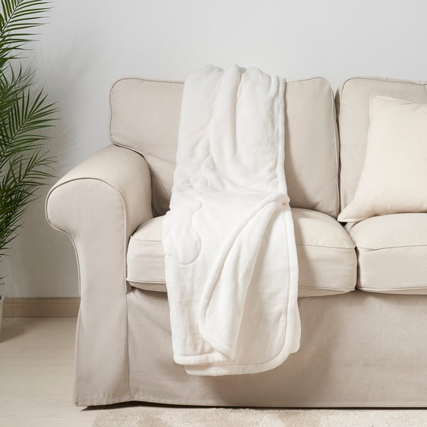 White fleece blanket draped on beige sofa, providing warmth and comfort.