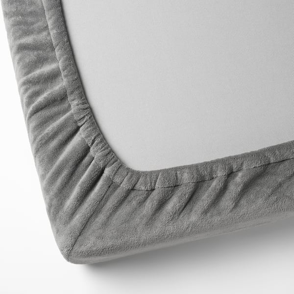 A cosy, grey fleece blanket with elastic corners, showcasing soft, plush texture.