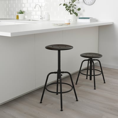 Two black KULLABERG stools by white counter, modern minimalist design, adjustable height, steel and wood, perfect for small spaces.