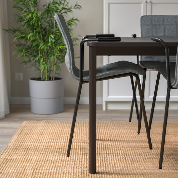 Three stacked office chairs, one off-center, on a rug next to a large green plant.