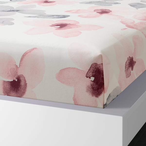 Flat sheet with flower pattern, folded neatly on white bed, showcasing pink and grey floral prints.