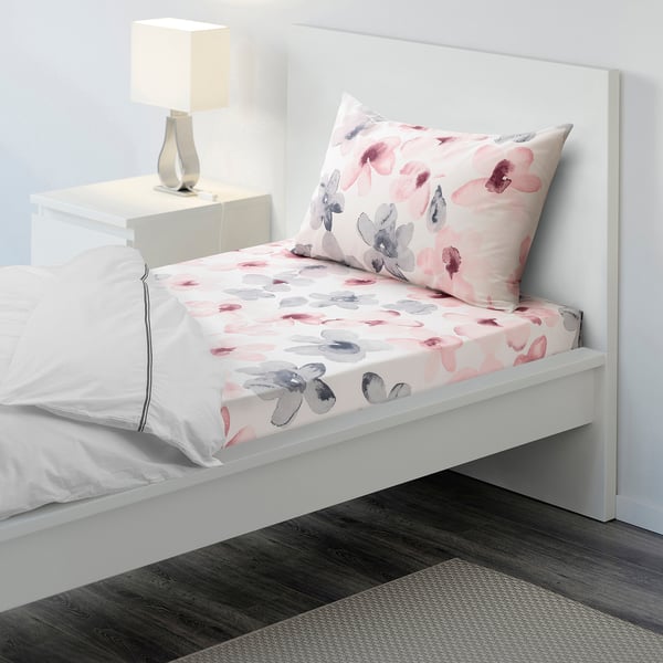 White bed with floral duvet, single pillow, matching decor pillow, cute lamp, crisp cotton-lyocell blend, modern headboard, cosy rug.