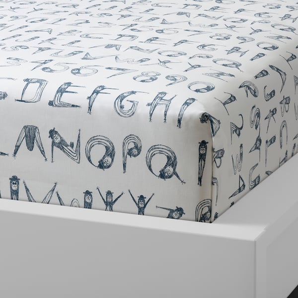 White toddler bed sheet with blue whimsical letter patterns. Soft, durable cotton fabric.
