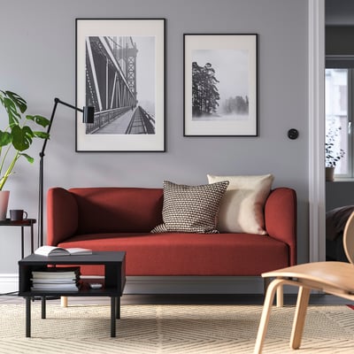 Modern living room with red LILLEHEM sofa, black chair, coffee table, and art prints.