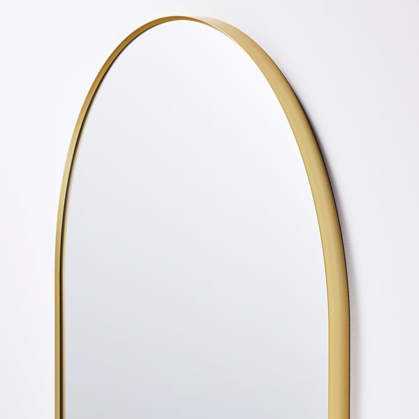 Elegant gold-framed mirror with rounded top, reflecting quality and style.