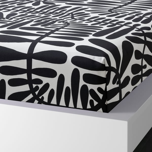 Black and white leaf-patterned bedsheet on white bed. Simple, nature-inspired design with breathable, moisture-absorbent fabric.
