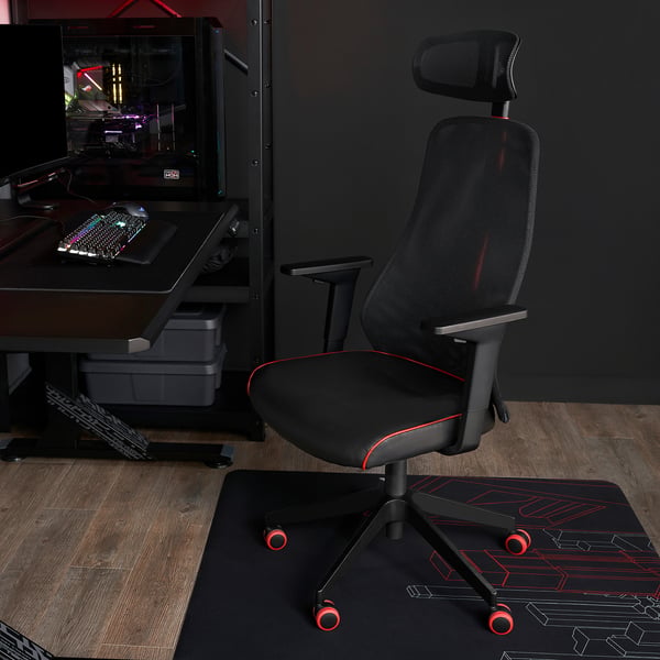 Black MATCHSPEL gaming chair with red accents sits beside a dark desk, larger than the small storage box, with an adjustable computer setup.