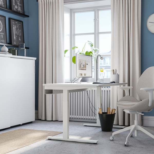 Modern home office with adjustable MITTZON desk, chair, & decor. Blue walls, large window, minimalist.