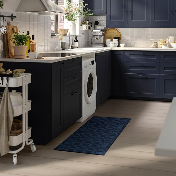 Modern kitchen with NATTÅG blue chequered rug, placing beside washing machine, capturing clean design.