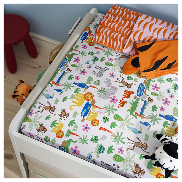 Childs bed with NATTHÄGER jungle print sheet; bright colours, animal designs; orange patterned blanket.