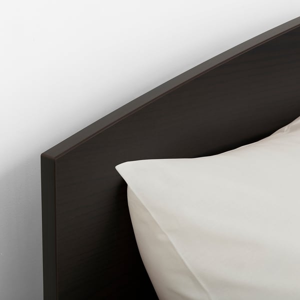 Dark wooden headboard with crisp white pillow, showcasing modern design and quality finish.