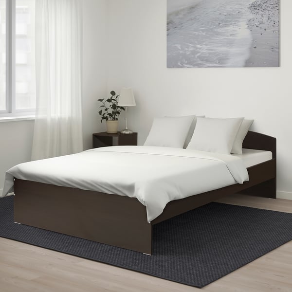 A NODELAND bed with dark frame and white bedding, rectangular and sleek, minimalist style.