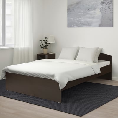 A NODELAND bed with dark frame and white bedding, rectangular and sleek, minimalist style.