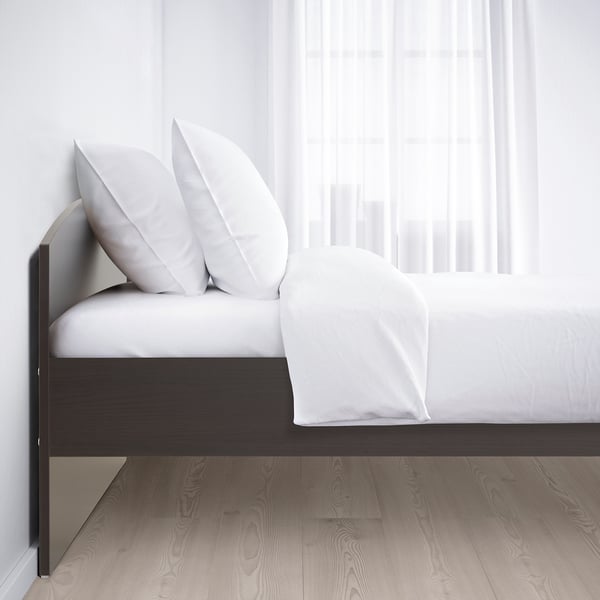 A modern bed with white pillows, a duvet, and dark frame. Sides adjust for varying mattress thickness.