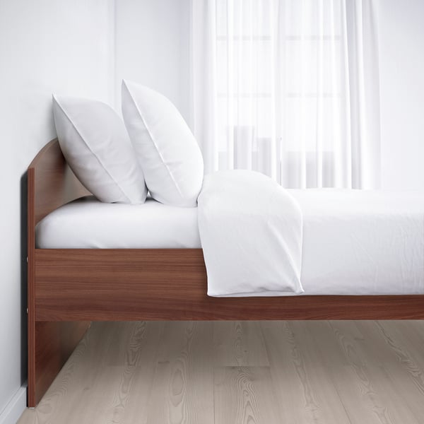 Minimalist bed with white pillows, blanket, adjustable wooden frame.