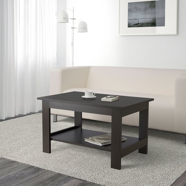 Modern living room with black coffee table, magazines, cup, and remote. Bright, cream decor.
