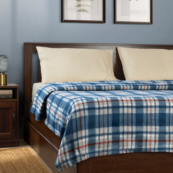 Blue & white chequered blanket on bed, made of recycled polyester. Two white pillows, bedside table with lamp, and two framed wall pictures.