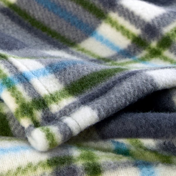 Close-up of soft, textured blanket with green, grey, and white pattern. Fabric appears cosy and well-woven.