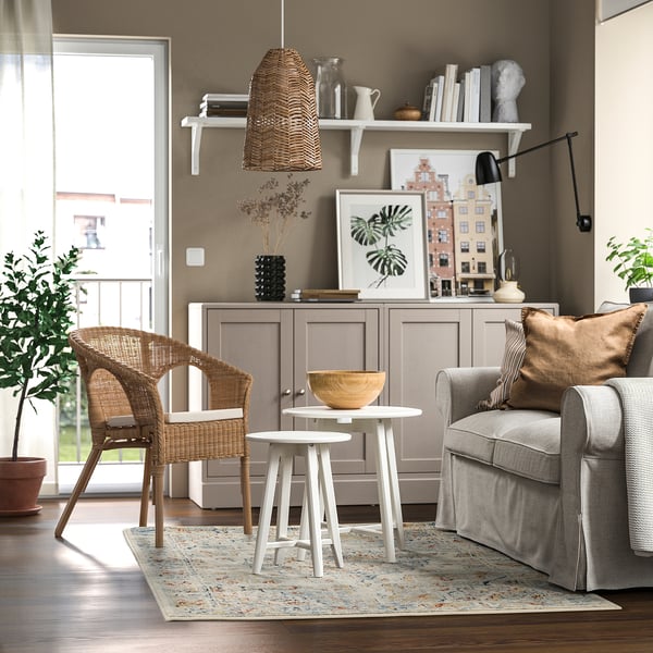 Living room with grey ONSEVIG carpet, woven chairs, and a cosy ambiance enhanced by natural light and decor.