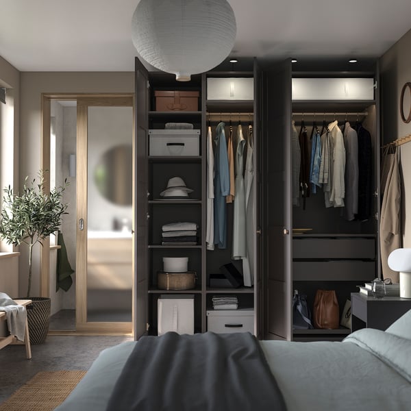 Bedroom with open wardrobe, clothes, shelves. Grey bed, pendant light, natural light.