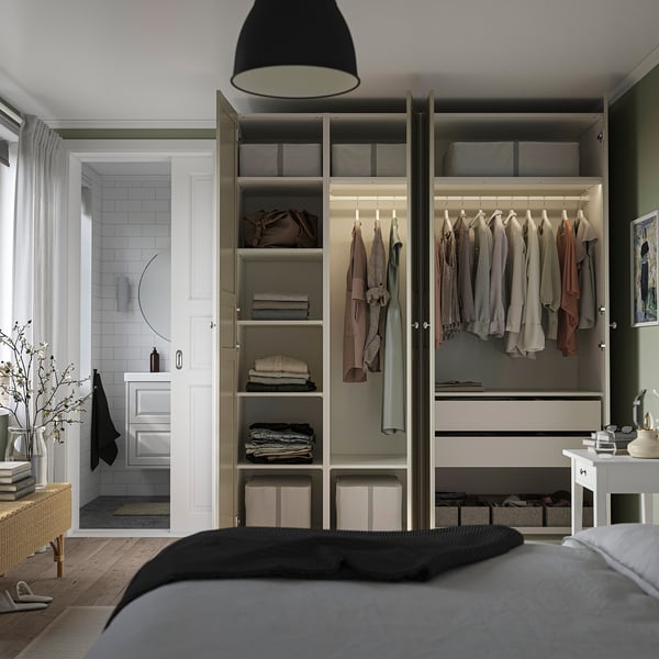 Modern bedroom with open closet showing clothes, folded items, and integrated lighting.