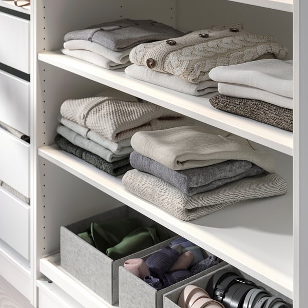 Organised closet with folded sweaters and socks in bins.